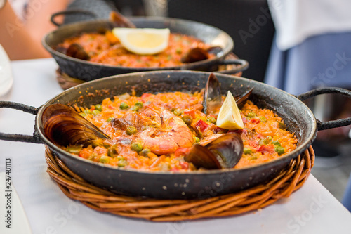 Delicious seafood paella on an iron pan. Rice, lemon, mussels, shrimp and vegetables