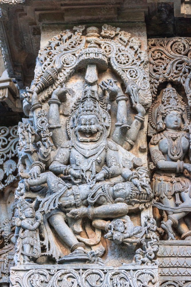 Halebidu, Karnataka, India - November 2, 2013: Hoysaleswara Temple of Shiva. Closeup of statue on side of main sanctuary, where Narasiṃha, Vishnu avatar, kills Hiraṇyakasipu, in bluish gray stone.