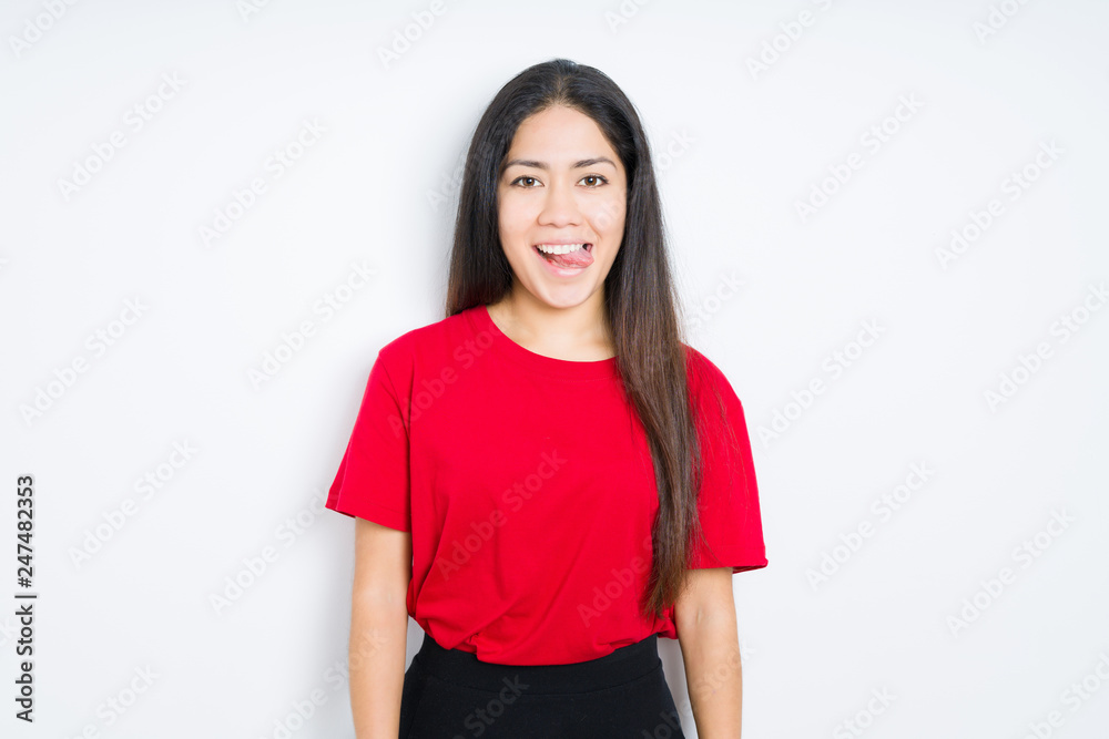 Beautiful brunette woman wearing red t-shirt over isolated background sticking tongue out happy with funny expression. Emotion concept. Beautiful brunette woman wearing red t-shirt over isolated background sticking tongue out happy with funny expression. Emotion concept.