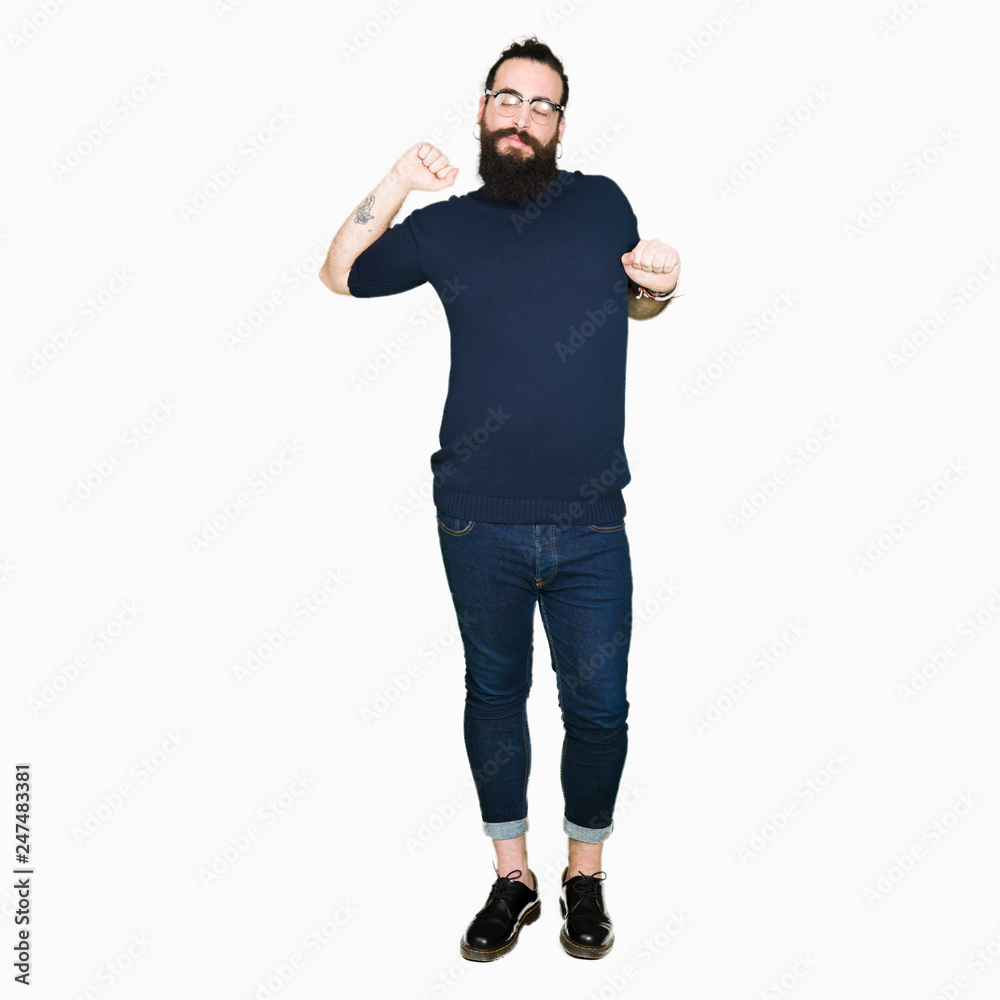 Naklejka premium Young hipster man with long hair and beard wearing glasses stretching back, tired and relaxed, sleepy and yawning for early morning