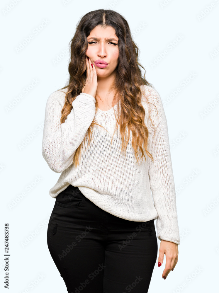 Young beautiful woman wearing white sweater touching mouth with hand with painful expression because of toothache or dental illness on teeth. Dentist concept. Young beautiful woman wearing white sweater touching mouth with hand with painful expression because of toothache or dental illness on teeth. Dentist concept.