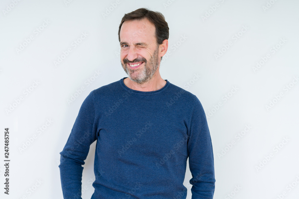 Fototapeta premium Elegant senior man over isolated background winking looking at the camera with sexy expression, cheerful and happy face.