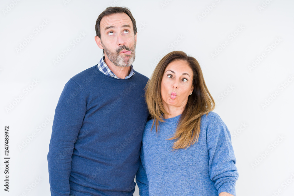 Beautiful middle age couple in love over isolated background making fish face with lips, crazy and comical gesture. Funny expression.