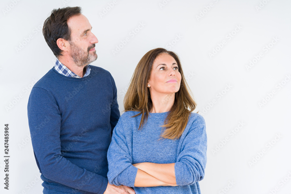 Beautiful middle age couple in love over isolated background smiling looking to the side with arms crossed convinced and confident Beautiful middle age couple in love over isolated background smiling looking to the side with arms crossed convinced and confident