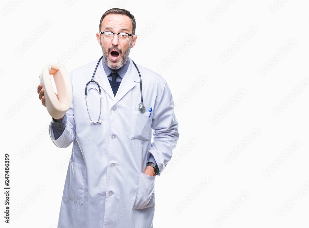 Middle age senior hoary doctor man holding neck collar over isolated background scared in shock with a surprise face, afraid and excited with fear expression Middle age senior hoary doctor man holding neck collar over isolated background scared in shock with a surprise face, afraid and excited with fear expression