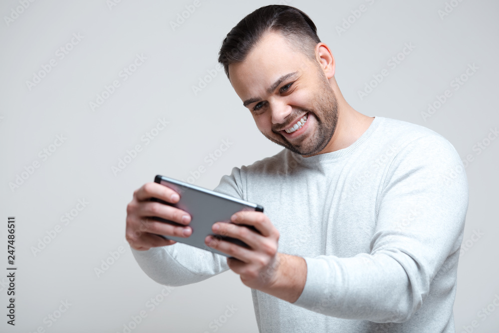 Joy man playing video games on smartphone over white background.