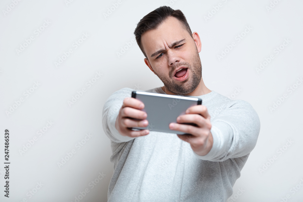 Happy screaming man playing video games on smartphone over white background Happy screaming man playing video games on smartphone over white background