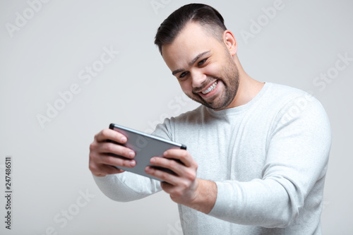 Joy man playing video games on smartphone over white background.