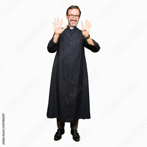 Middle age priest man wearing catholic robe showing and pointing up with fingers number nine while smiling confident and happy.