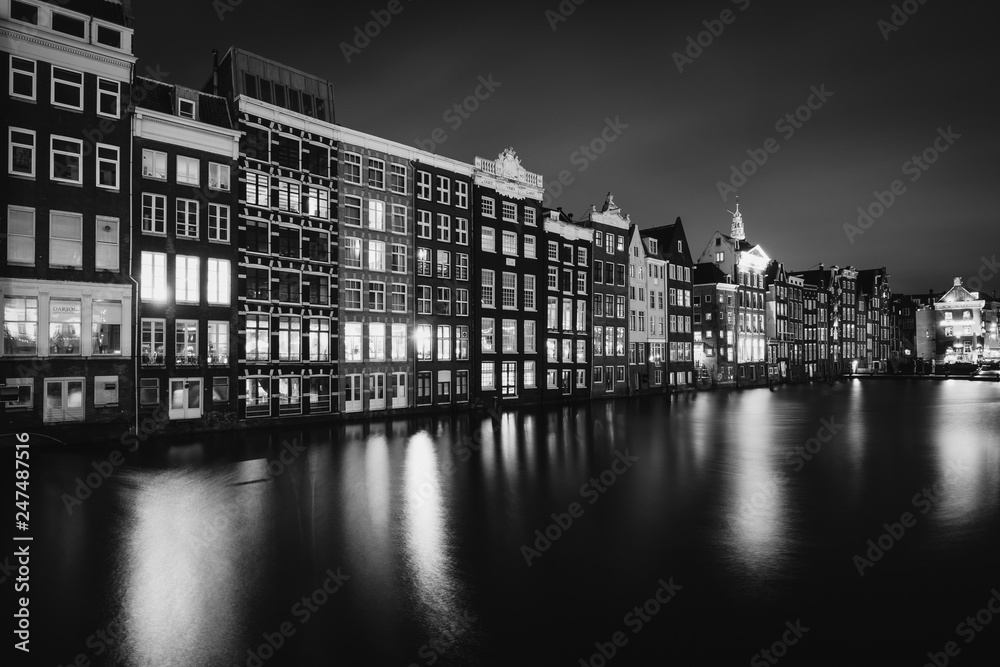 Buildings along the Damrak canal at night, in Amsterdam, The Netherlands.