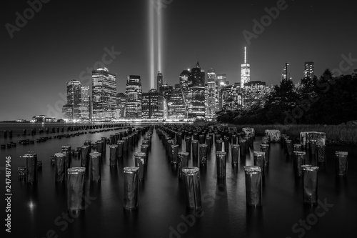 Pier pilings and the Tribute in Light over the Manhattan skyline at night, seen from Brooklyn Bridge Park, in Brooklyn, New York. photo