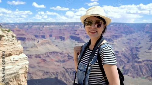 Travel hiking young beautiful teenager student face camera smiling attractive while sightseeing at Grand Canyon viewpoint in Arizona USA. charming girl traveler in sunglasses joyful visit nature. photo