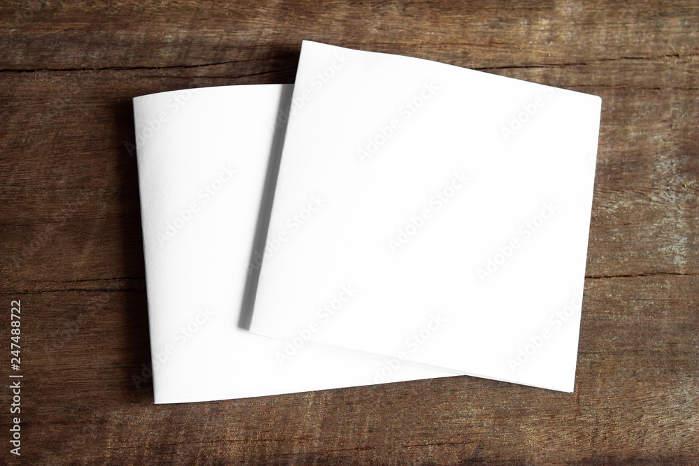 Blank portrait mock-up paper. brochure magazine isolated on brown wooden table, changeable background / white paper isolated on wood Blank portrait mock-up paper. brochure magazine isolated on brown wooden table, changeable background / white paper isolated on wood