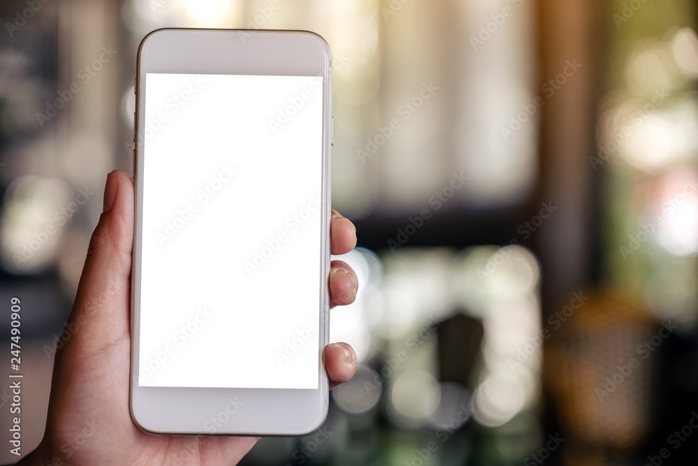 Mockup image of a hand holding and showing a white mobile phone with blank screen with blurred background in cafe Mockup image of a hand holding and showing a white mobile phone with blank screen with blurred background in cafe