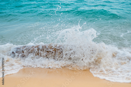 The waves hit the timber between the orange sand and the blue sea.