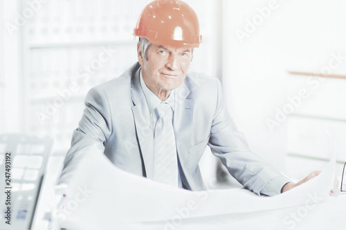 Portrait of professional architect with blueprints sitting behin photo