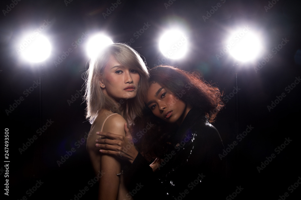 Two Fashion Young thin Asian Woman Tan skin eyes beautiful make up fashion dress lesbian look posing attractive glam look. Studio Lighting Dark Background smoke fog back rim light low exposure Two Fashion Young thin Asian Woman Tan skin eyes beautiful make up fashion dress lesbian look posing attractive glam look. Studio Lighting Dark Background smoke fog back rim light low exposure
