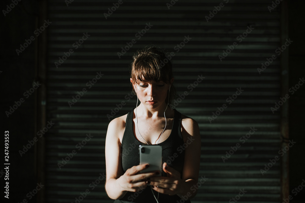 © Rawpixel.com - Sporty woman listening to music in a dark alley © Rawpixel.com - Sporty woman listening to music in a dark alley