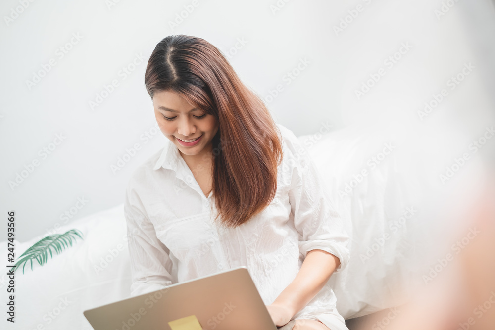 Beautiful Asian woman using laptop and smart phone in bed room for online shopping, Asian woman lifestyle concept Beautiful Asian woman using laptop and smart phone in bed room for online shopping, Asian woman lifestyle concept