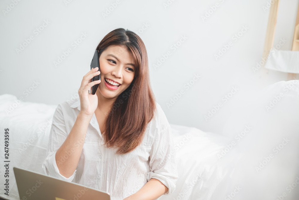 Beautiful Asian woman using laptop and smart phone in bed room for online shopping, Asian woman lifestyle concept Beautiful Asian woman using laptop and smart phone in bed room for online shopping, Asian woman lifestyle concept