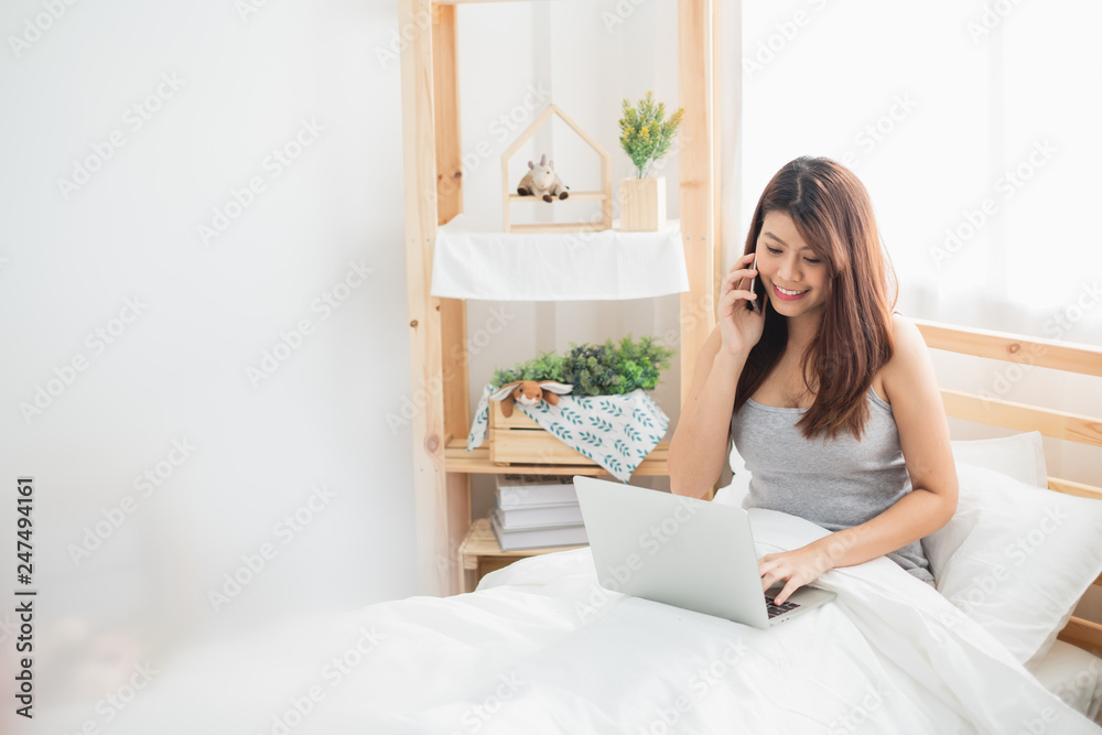 Beautiful Asian woman using laptop and smart phone in bed room for online shopping, Asian woman lifestyle concept Beautiful Asian woman using laptop and smart phone in bed room for online shopping, Asian woman lifestyle concept