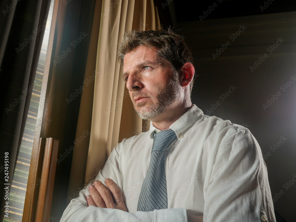 Fototapeta premium office portrait of businessman working late looking worried through window thoughtful and pensive feeling sad and depressed thinking and considering business problem