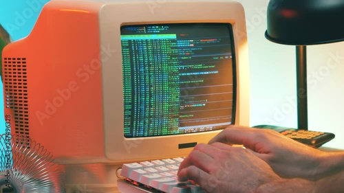 Hacker in the 80s 90s hacking a computer retro style. He even takes his vintage phone.