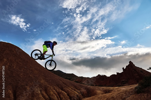 Cyclist riding a mountain bike downhill style in a canyon  Skazka  that looks like a Martian landscape. Issyk-Kul  Kyrgyzstan.