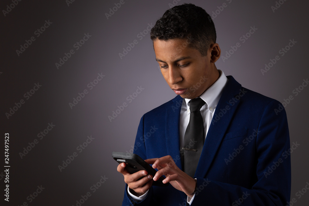 Hispanic Teenager Dressed Well Dressed in Suit, and Using Cellphone, Smartphone Hispanic Teenager Dressed Well Dressed in Suit, and Using Cellphone, Smartphone