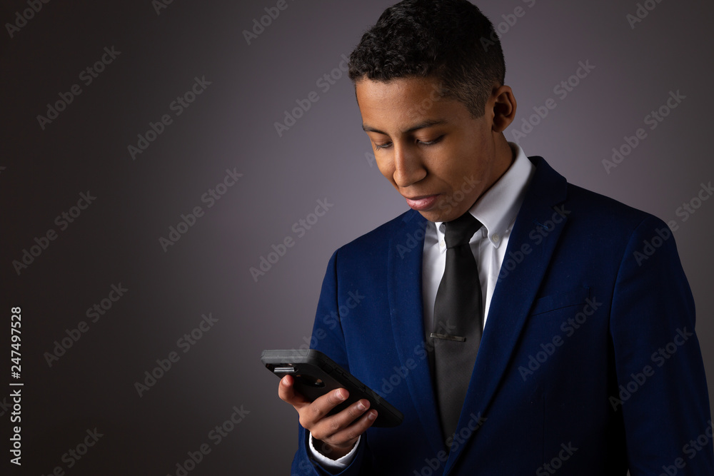 Hispanic Teenager Dressed Well Dressed in Suit, and Using Cellphone, Smartphone Hispanic Teenager Dressed Well Dressed in Suit, and Using Cellphone, Smartphone