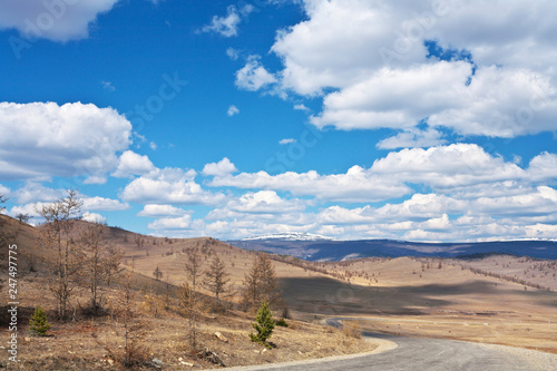 The road along the Tazheranskaya steppe to Lake Baikal. Spring landscape on the background of a beautiful sky with cumulus clouds © Katvic