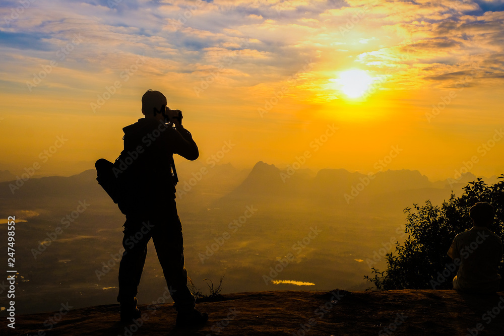 Man backpacker with her dslr camera silhouette in sunset background