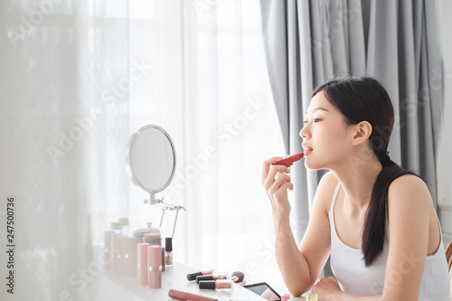 Young beautiful Asian woman applying cosmetics make up on her face  health beauty skin care and make up concept