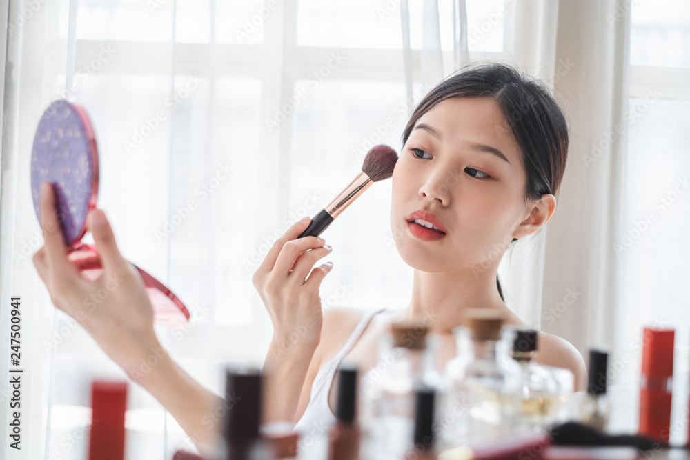 Young beautiful Asian woman applying cosmetics make up on her face, health beauty skin care and make up concept Young beautiful Asian woman applying cosmetics make up on her face, health beauty skin care and make up concept
