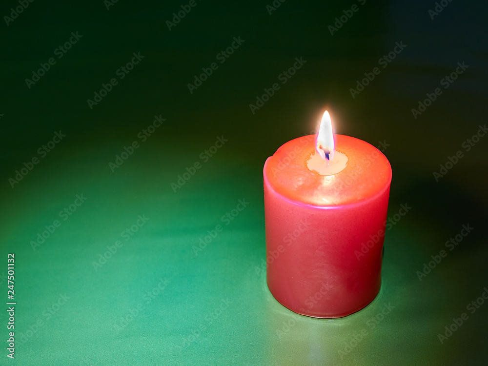 Red wax festive romantic burning candle on a green decorative background. love symbol. festive mood. romantic dinner. copy space Red wax festive romantic burning candle on a green decorative background. love symbol. festive mood. romantic dinner. copy space