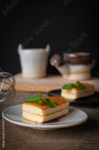 layer vanilla flavoured cake place on white plate on the wooden table there are black plate and