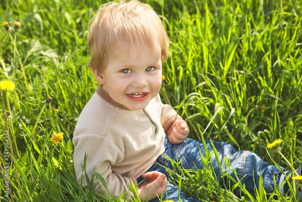 Happy childhood outdoor, little blond boy in green grass Happy childhood outdoor, little blond boy in green grass