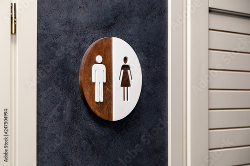 Toilet, wc icon, round wooden white and brown sign on restroom door in the hallway, restaurant, lobby. Concept sign of toilet room at airport, cafe, bar, hotel, train station