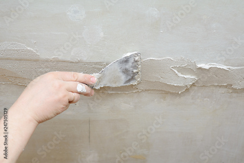 Male hand holds trowel, closing up cracks in the ceiling.