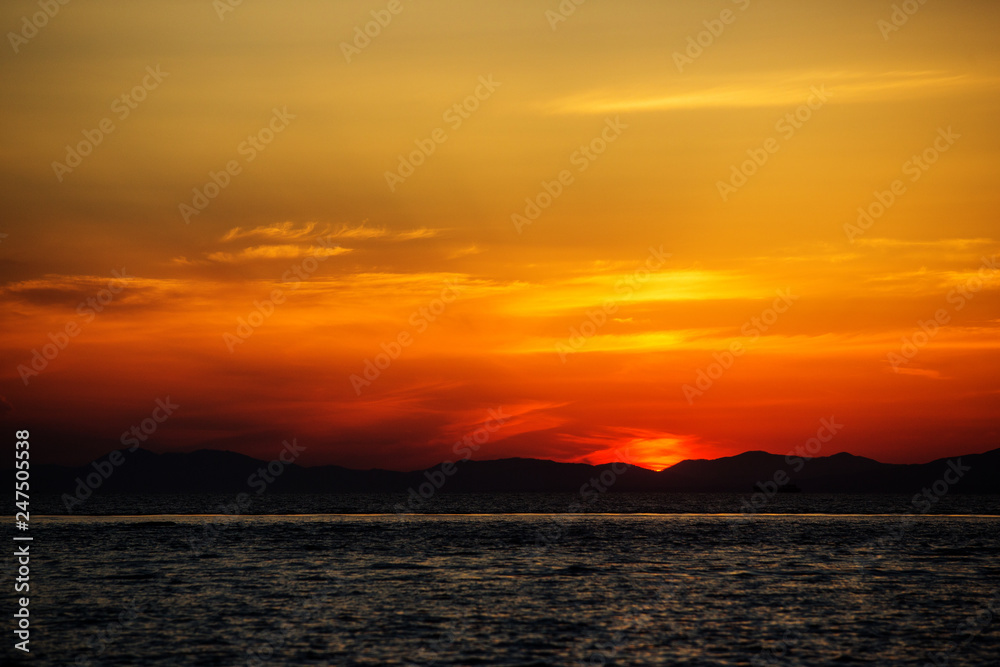 Beautiful bright sunset on the sea. A lone boat and yacht drift in the background of the sunset.