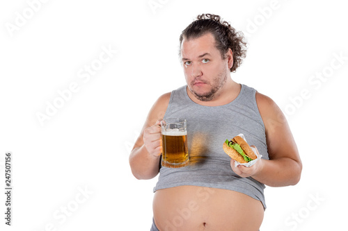 Funny fat man eating burger and drinking alcohol beverage on white background