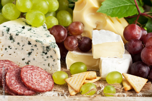 Various types of cheese and fruits on dark surface