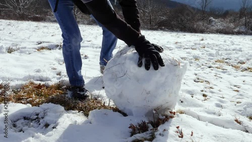 Person Rolling Giant Snowball in Snow Covered Grass Field photo