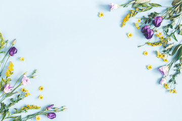 Flowers composition. Yellow and purple flowers on pastel blue background. Spring, easter concept. Flat lay, top view, copy space