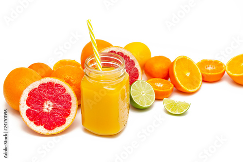 Freshly blended yellow and orange fruit smoothie in glass jar. Glass jar mugs with orange health smoothie, lime, grapefruit, lemon, tangerine. Selective focus. Copy space. Vegetarian food concept.  