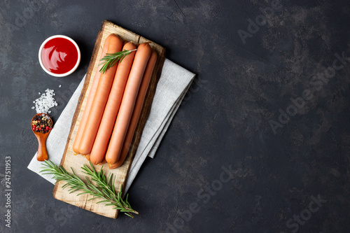 Принти на полотні Raw frankfurter sausages with ketchup on cutting board