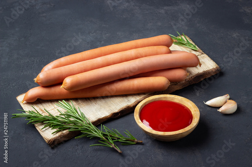 Принти на полотні Raw frankfurter sausages with ketchup on cutting board