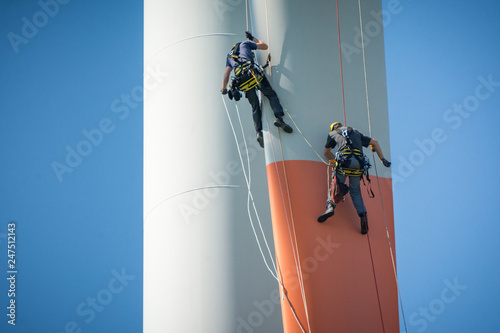 Fotografie Inspection engineers abseiling down a rotor blade of a wind turbine in a North G