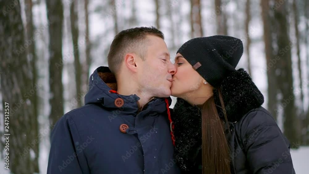 Close-up of a man and a woman in love standing in the winter forest hugging each other and looking into the distance Close-up of a man and a woman in love standing in the winter forest hugging each other and looking into the distance