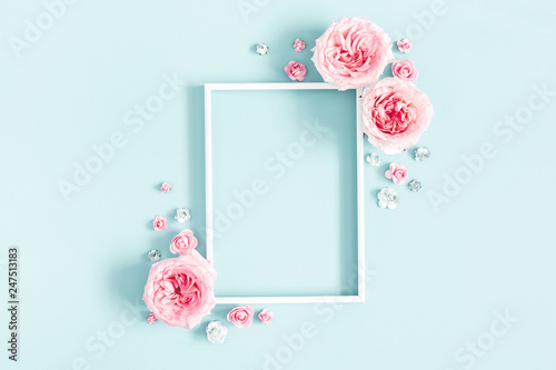 Flowers composition. Photo frame, rose flowers on pastel blue background. Valentines day, mothers day, womens day, spring concept. Flat lay, top view, copy space